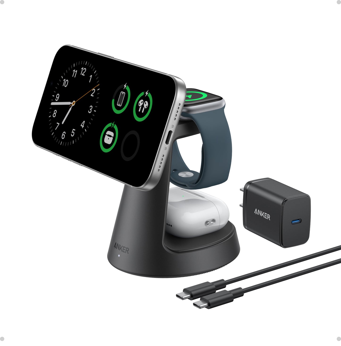The black Anker MagGo Wireless Charging Station (3-in-1, Dock Stand) wirelessly charges a smartphone, smartwatch, and earbuds. A phone on the stand shows a clock and battery icons. Nearby are a USB-C wall adapter and two USB-C cables.