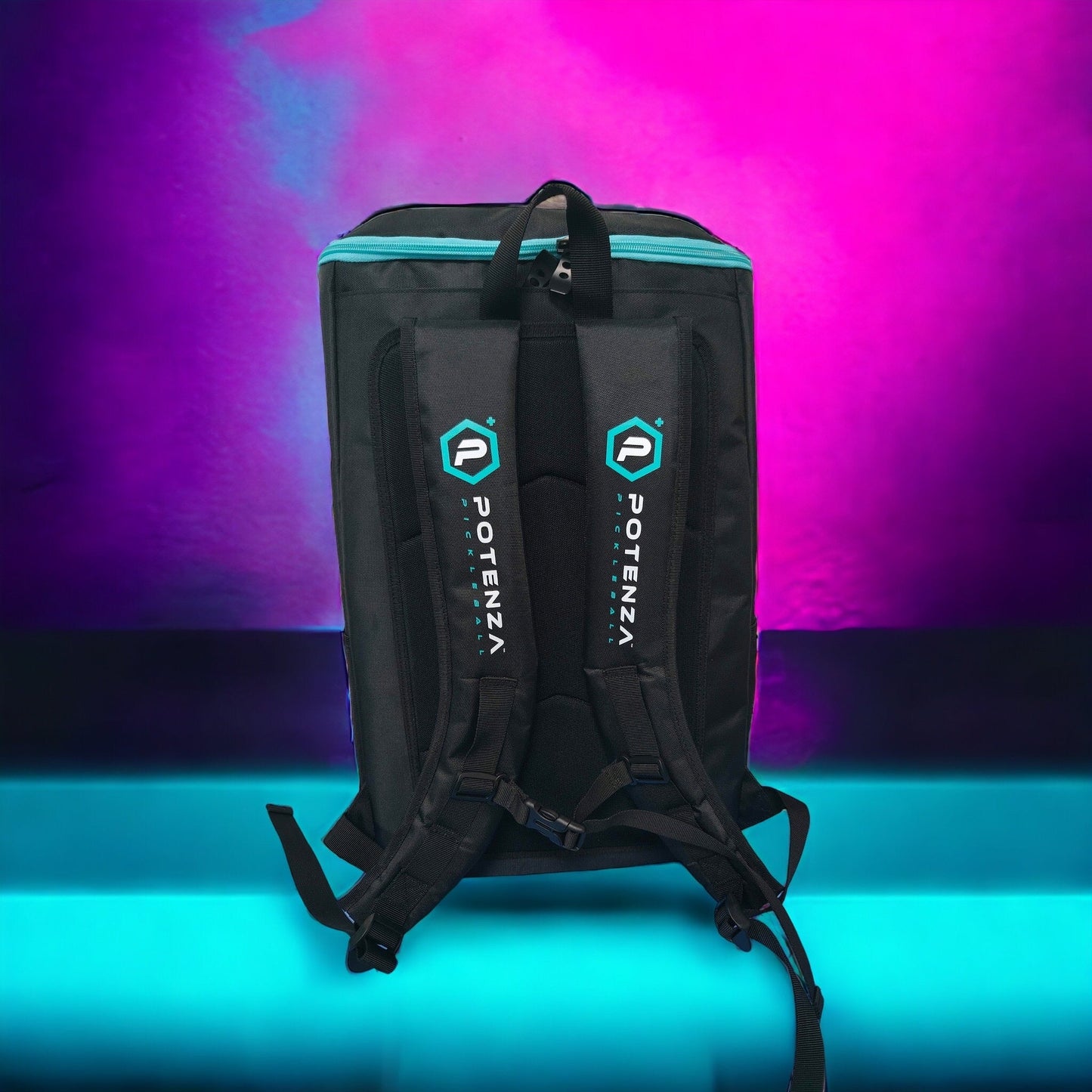 A black Potenza Pickleball Pro Player Logo Bag with blue accents and dual padded straps stands upright on a glowing turquoise surface. This modern backpack holds 4-5 paddles, features visible zippers, and includes a handy shoe compartment.