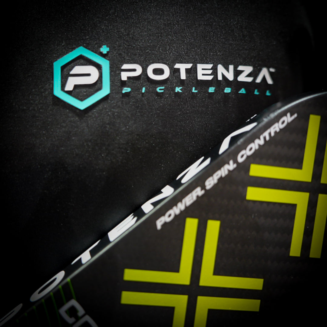 Close-up of a Potenza Pickleball paddle with bold yellow-green lines and "POWER. SPIN. CONTROL." text, in front of the Sport Athletic Polo (Quarter Zip Collar) BLACK by Potenza Pickleball, both featuring the brand logo.