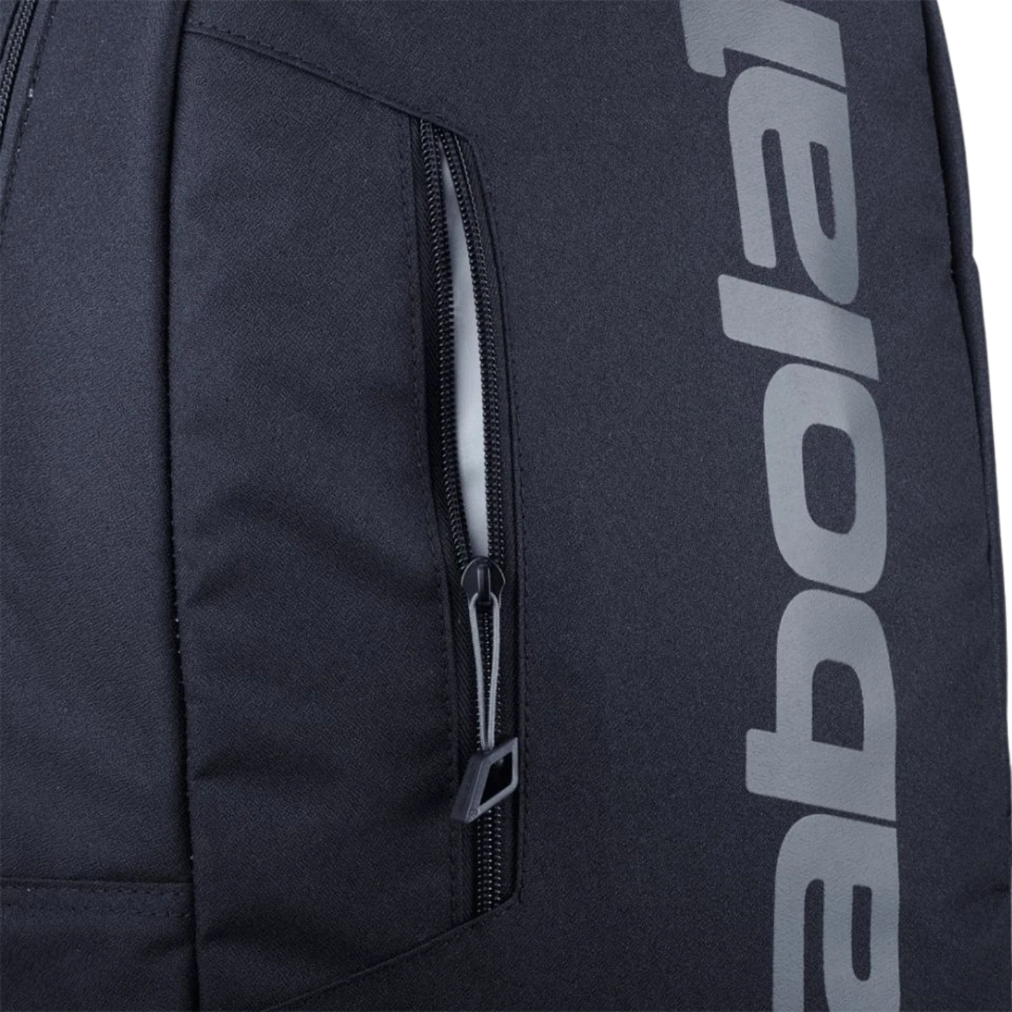 Close-up of the Babolat COURT Backpack LITE by Padel USA, made from recycled materials. It features a sleek black zipper pull tab and a vertical zipper pocket with "Babolat" in bold gray letters printed vertically on the right side.