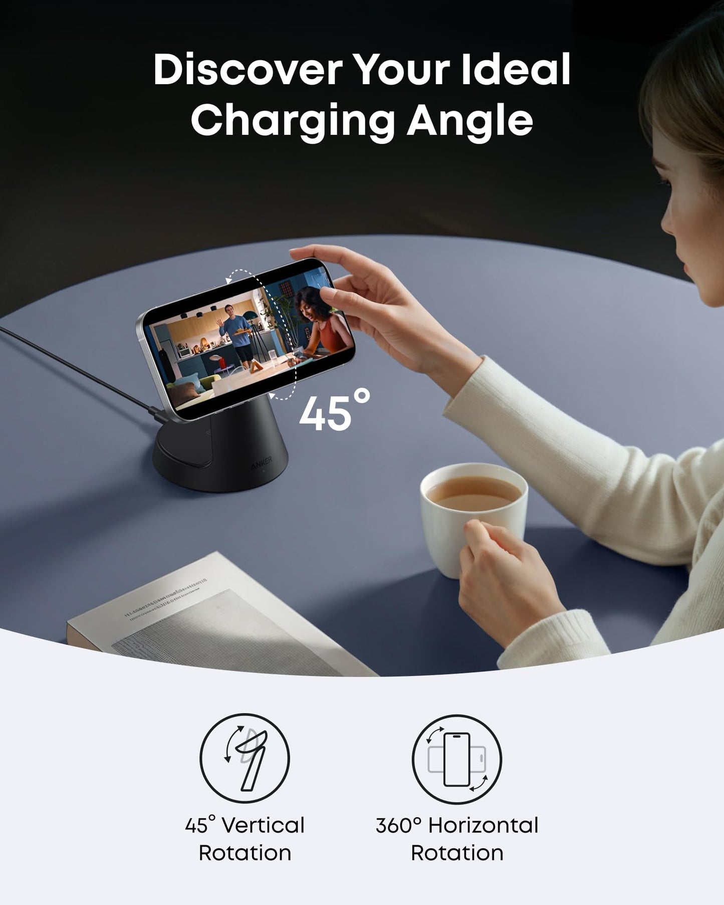 A person sits at a round blue table, watching a video on a smartphone mounted on the Anker MagGo Wireless Charging Station (3-in-1, Dock Stand) tilted at 45°, with coffee and a book nearby. Text above reads “Discover Your Ideal Charging Angle.” Rotation icons below.