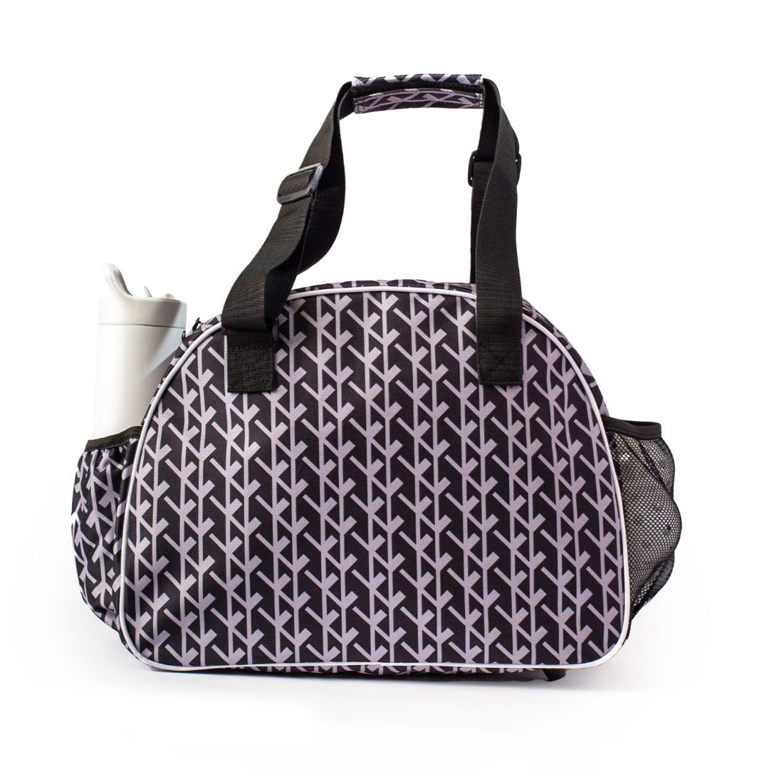 The Court Couture Black Premium Women's Pickleball Bag by Pik'le'Ball Sports features a black and white geometric leaf pattern, short black handles, a detachable shoulder strap, a side pocket for a bottle, and a mesh pocket on the other side.