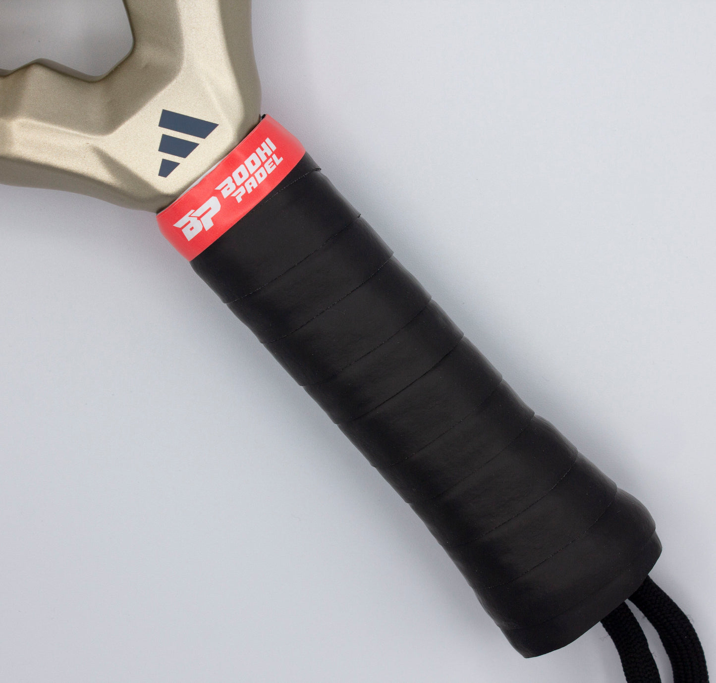 Close-up of a black-wrapped handle with PROtack™ Premium Padel Overgrips by Bodhi Performance. The grip is tightly wound for moisture control, featuring a red "BP 300HI PADEL" band and a gold section with the black Adidas logo against a light gray background.
