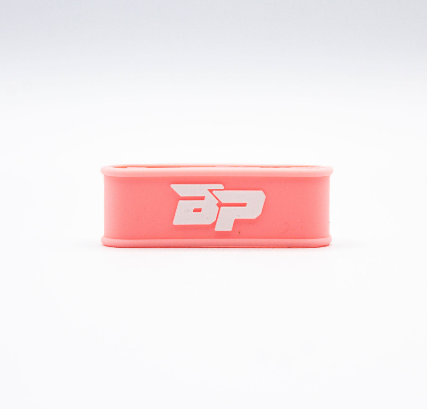 A pink Bodhi Performance Paddle Band with rounded edges is displayed on a white background. This minimal silicone pickleball paddle accessory features a bold white BP logo in uppercase at its center.