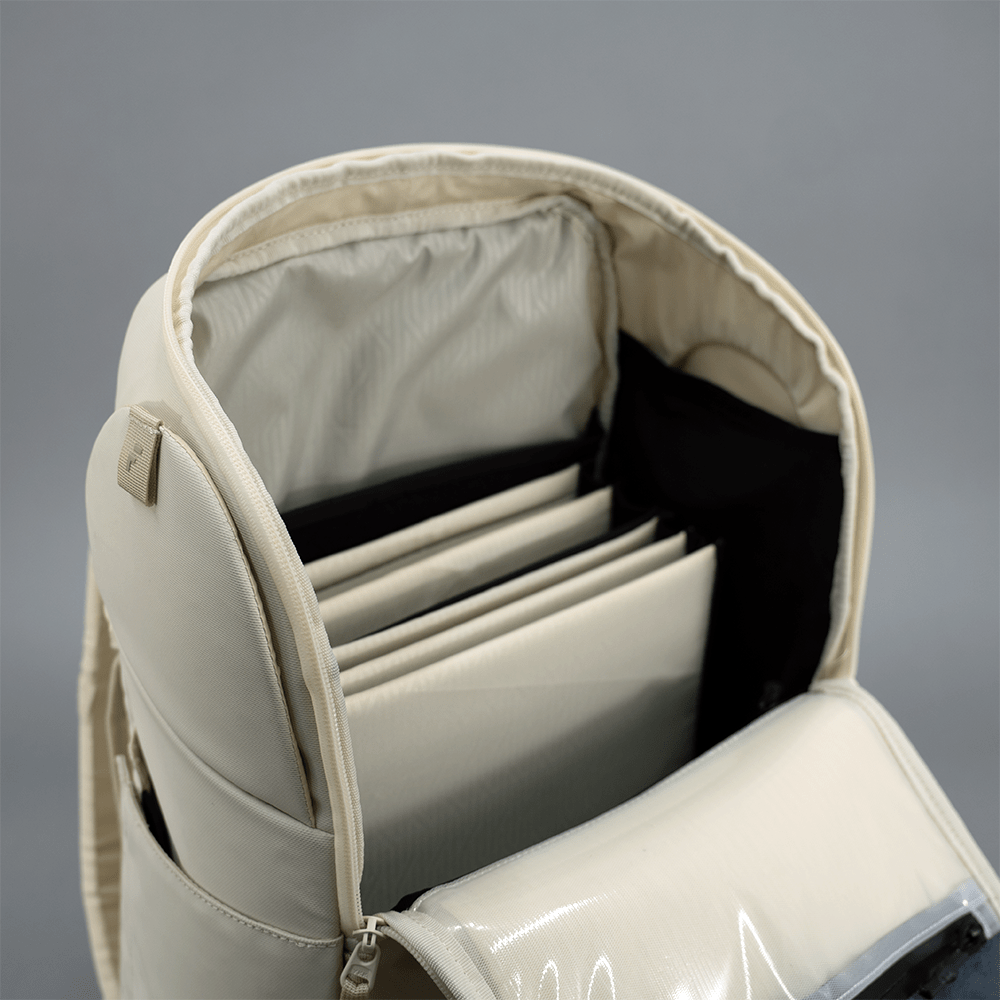 The FORWRD Court Caddy Pickleball Bag in cream showcases premium materials, a spacious modular interior with beige file folders in separate slots, a zippered inner compartment, and a smooth, glossy texture against a plain gray background.