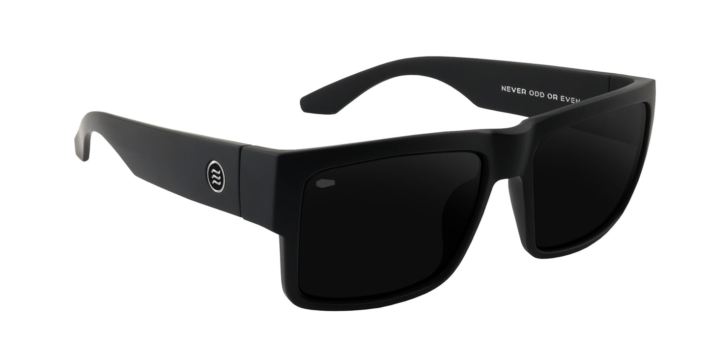 Black rectangular Relic sunglasses by Neven Eyewear with wide arms and a small circular temple logo. Dark-tinted lenses and "NEVER ODD OR EVEN" text inside nod to Tim Howley's style. Shown on a plain white background.
