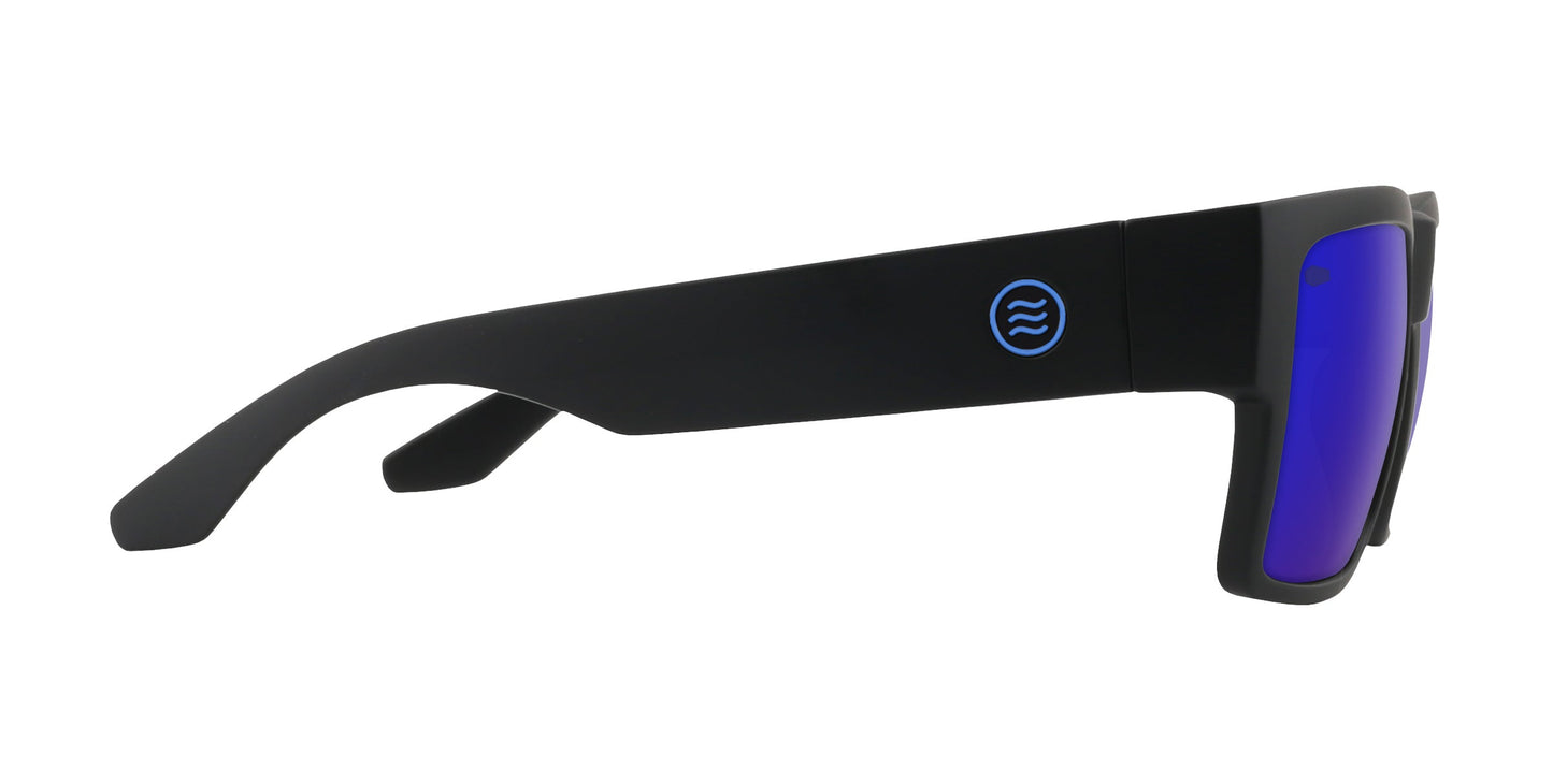 A pair of Neven Eyewear Scythe sunglasses with thick matte black frames, reflective blue-purple lenses, and a circular blue logo with wavy lines on the arm create a bold gothic look when viewed from the side.