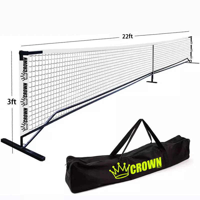 The 22-foot by 3-foot CROWN PICKLEBALL Full-Size Net (White/Black) from Crown Pickleball stands on sturdy black poles. A black carrying bag with a yellow crown logo and bright green CROWN lettering is ready for your next court setup.