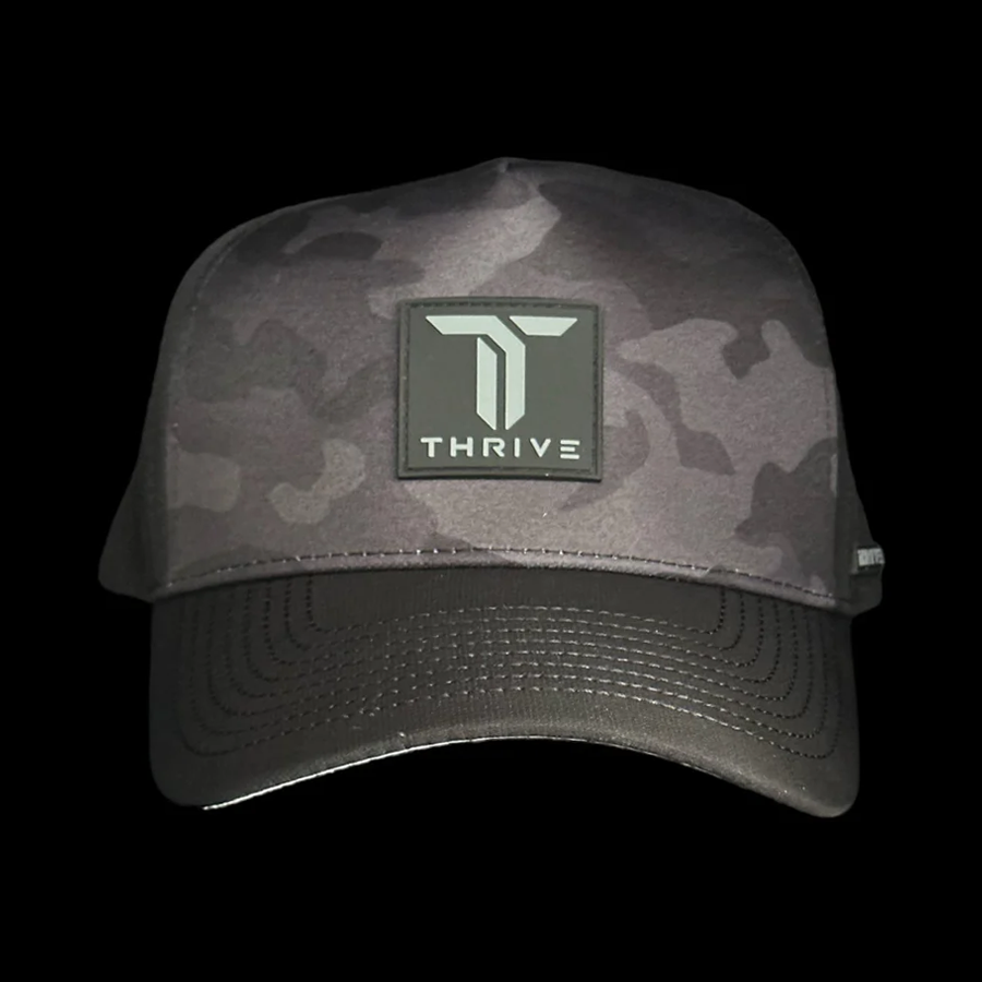 The Thrive Elite Tour Hat by Thrive Pickleball is a black camo cap with a structured front, featuring a large, square black patch with a bold white "T" logo above "THRIVE," all centered on the solid black background.