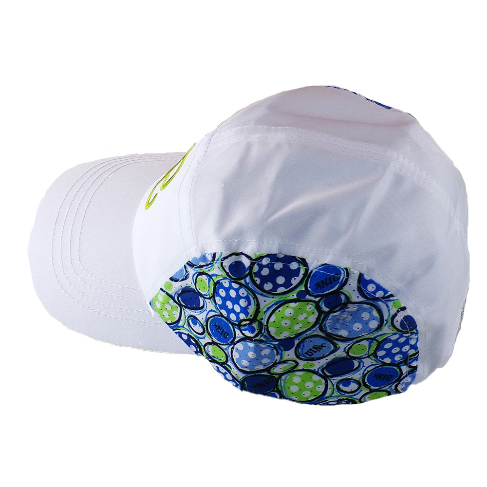 The PB Cap Dink 1 by Pickleball Bella is a white adjustable velcro cap featuring a colorful circular pattern with blue, green, and white polka-dotted circles and text on mesh side and back panels; the front and bill are plain white.