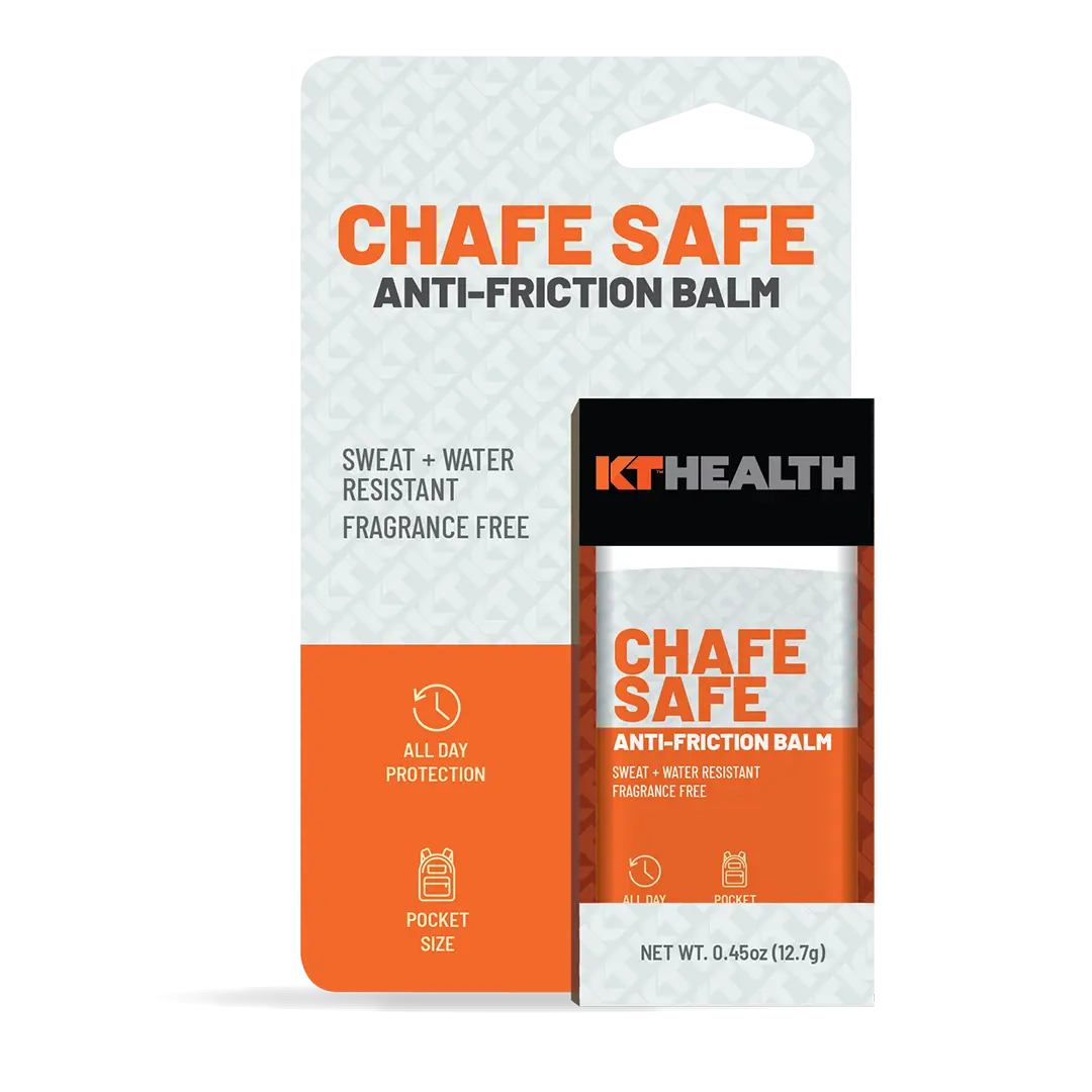 A KT Tape Chafe Safe™ Anti-Friction Balm 0.45oz tube is shown before the box with an orange and gray design, highlighting “All Day Protection,” “Chafing Protection,” and “Blister Prevention.”.