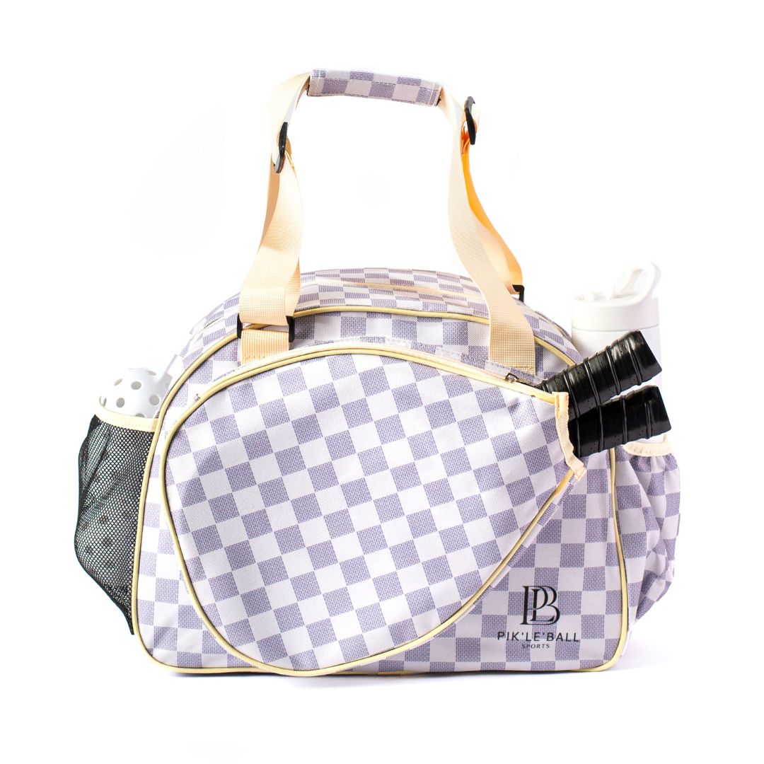 The Pik'le'Ball Sports Checkered Chic Premium Women's Pickleball Bag features cream handles, a large pocket for two black-handled paddles, mesh side pocket for balls and water bottle, padded compartments, adjustable strap, and "Pickleball" labeled on the front.