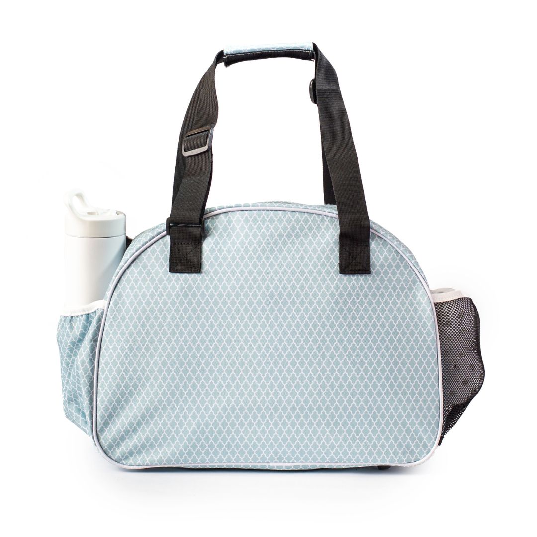 The Classy Sage Premium Women's Pickleball Bag by Pik'le'Ball Sports features a light blue geometric diamond design, black handles, a rounded top, a white travel mug in the left pocket, and a black mesh pocket on the right.