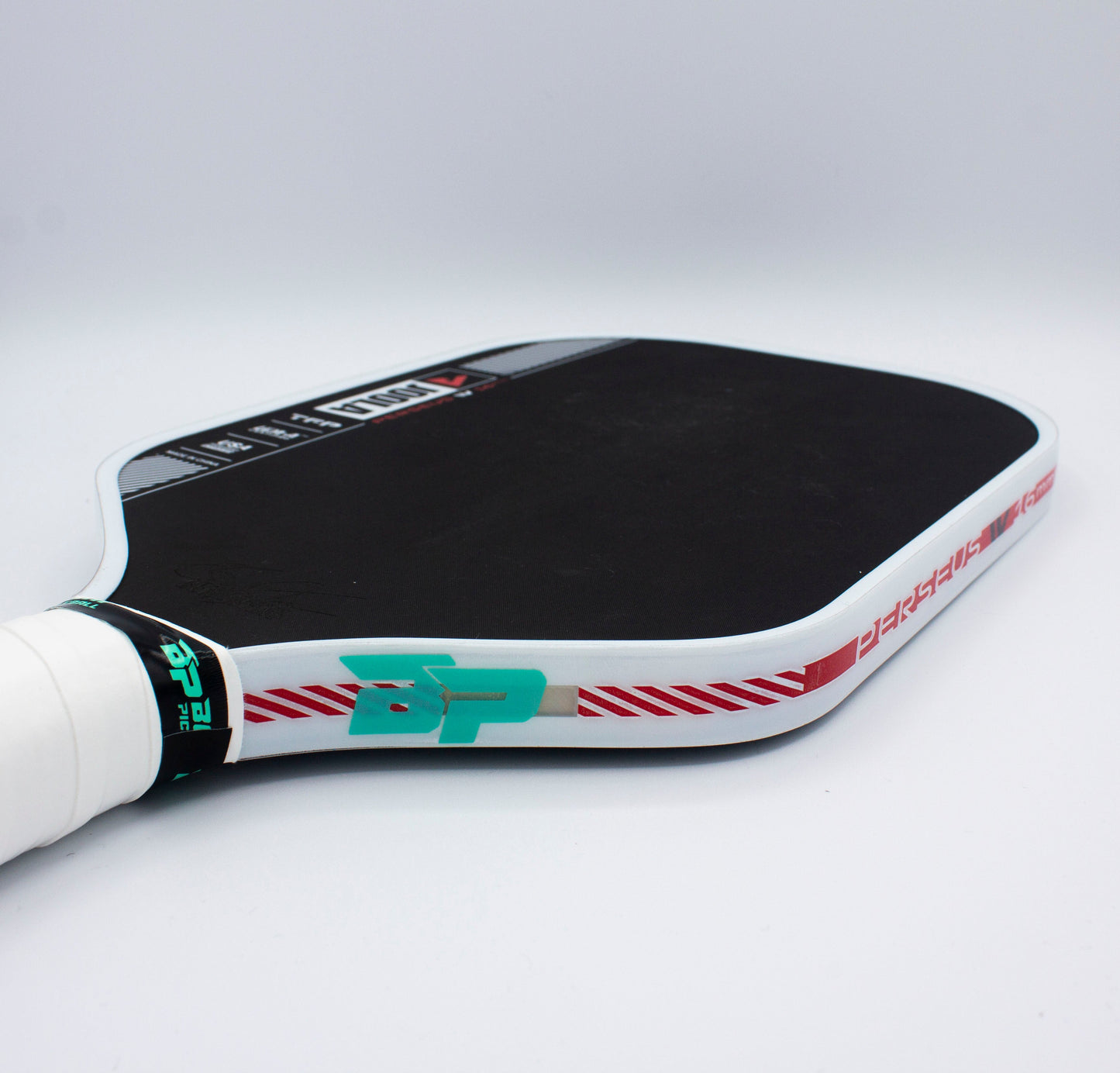Close-up view of Bodhi Performance’s Premium Edge Tape - CLEAR on a pickleball paddle with a white grip, black face, red diagonal lines, teal BP initials, and durable tape for protection. “Bodhi Performance” branding stands out against the plain background.