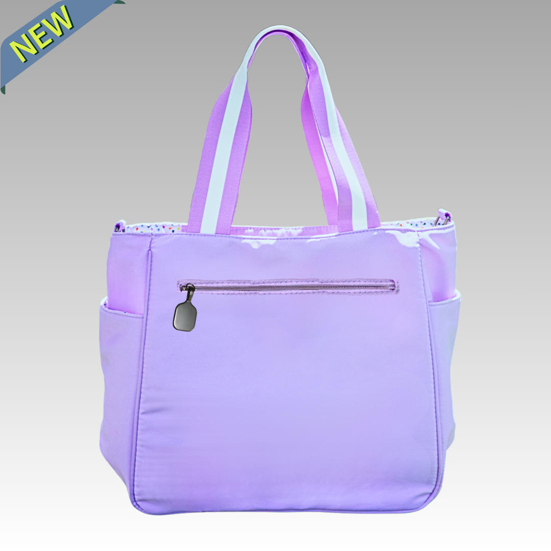 The Playly Store Lulu Pickleball Tote features lavender with striped handles, front zip pocket, side pockets, and a multicolored polka dot lining. A yellow "NEW" label appears top left on a gray gradient background.