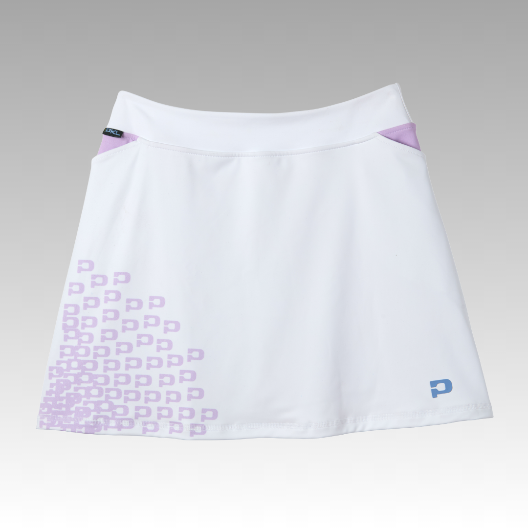 The Playly Store Sammy Skort 2.0 is a white pickleball skort with a slight A-line cut, lavender waist accents, and clustered “P” logos at the lower left. Made from CoolFlow fabric, it combines stylish court fashion with performance. Shown on a smooth grey gradient background.