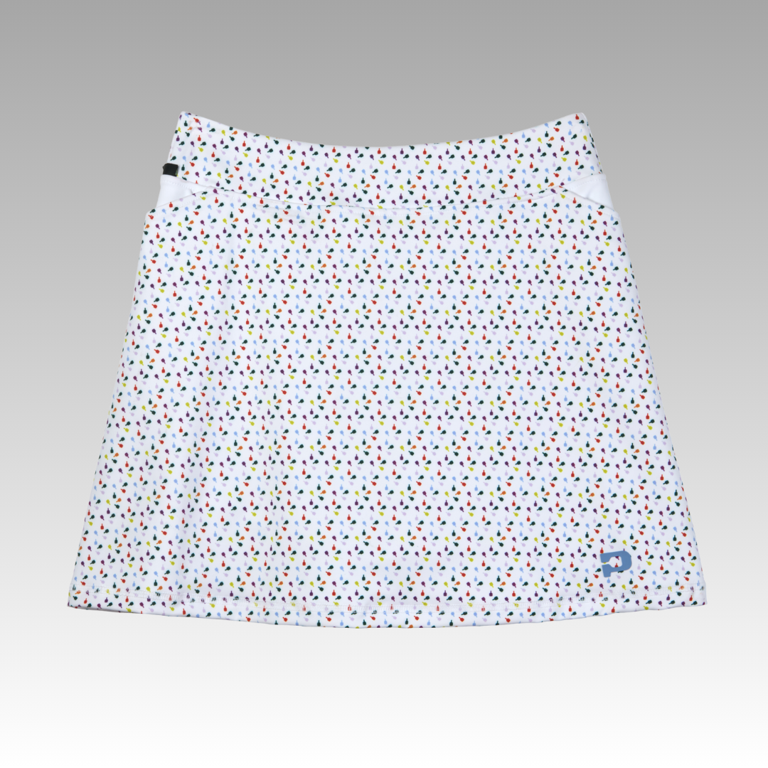 The Playly Store Sammy Skort 2.0 is a white A-line pickleball skort with multicolored polka dots, CoolFlow fabric, two white triangular side panels, and a blue logo near the hem, shown on a gray gradient background.