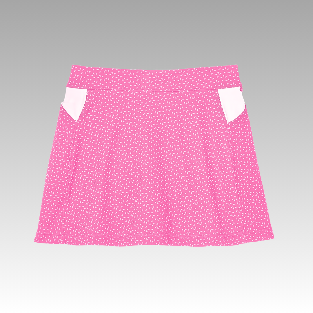 The Sammy Skort 2.0 by Playly Store features a pink high-waisted design with white polka dots, two white side pockets, and is made from CoolFlow fabric. Displayed against a gray gradient background.