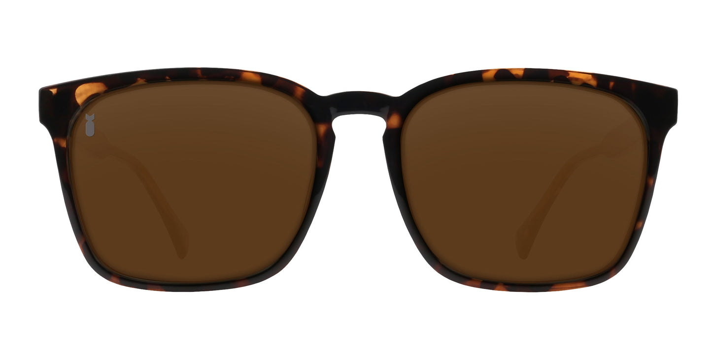 The Chazz sunglasses by Neven Eyewear feature a rectangular tortoise shell frame in dark brown and amber from the Divebomb Collection, with solid brown lenses, shown front-facing on a white background.