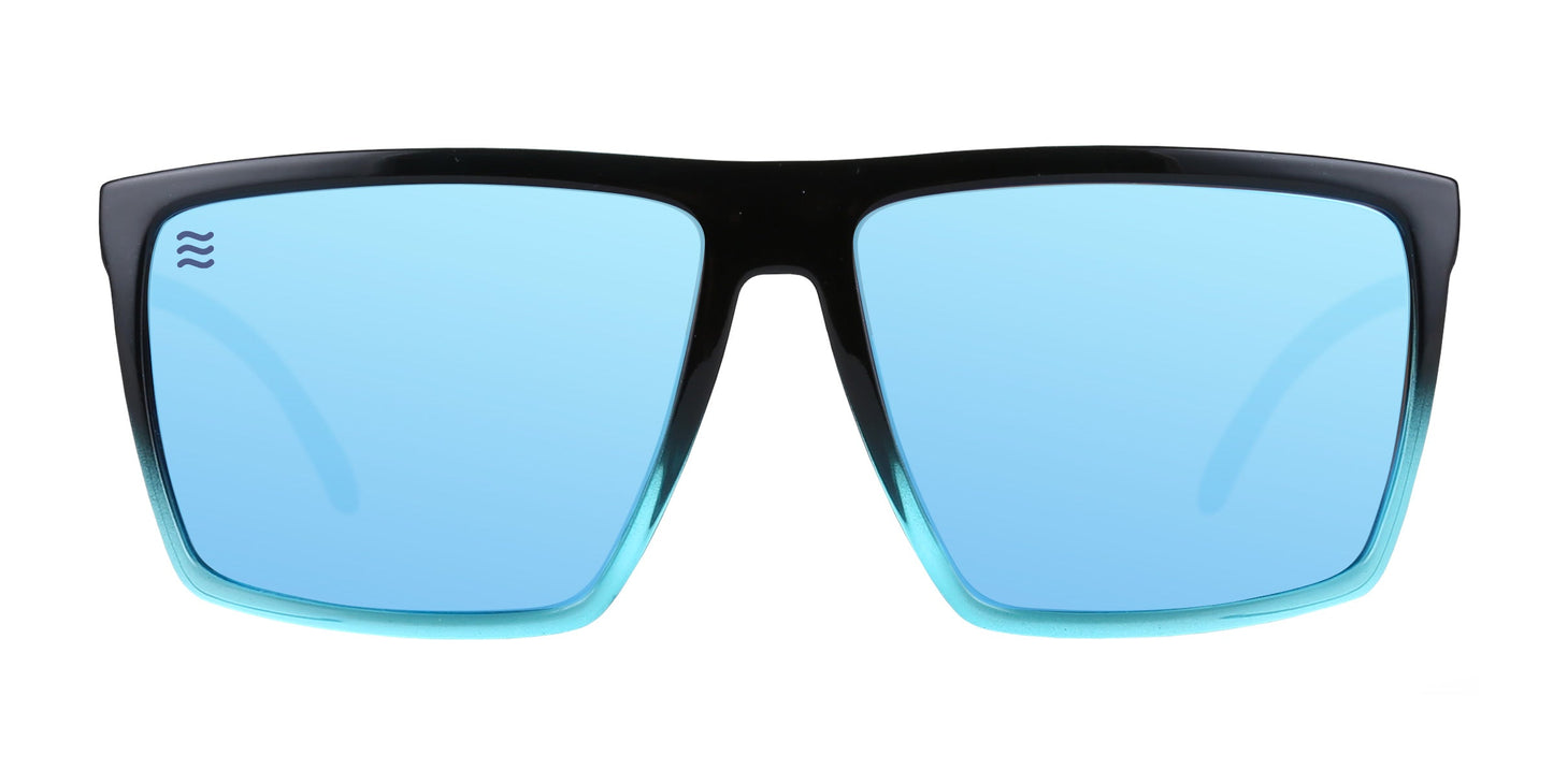 Neven Eyewear’s Arizona sunglasses feature a rectangular shape and glossy black frames fading to teal. The large, flat blue-tinted lenses provide UV400 protection with a subtle wave logo on the left. Shot on a plain white background.