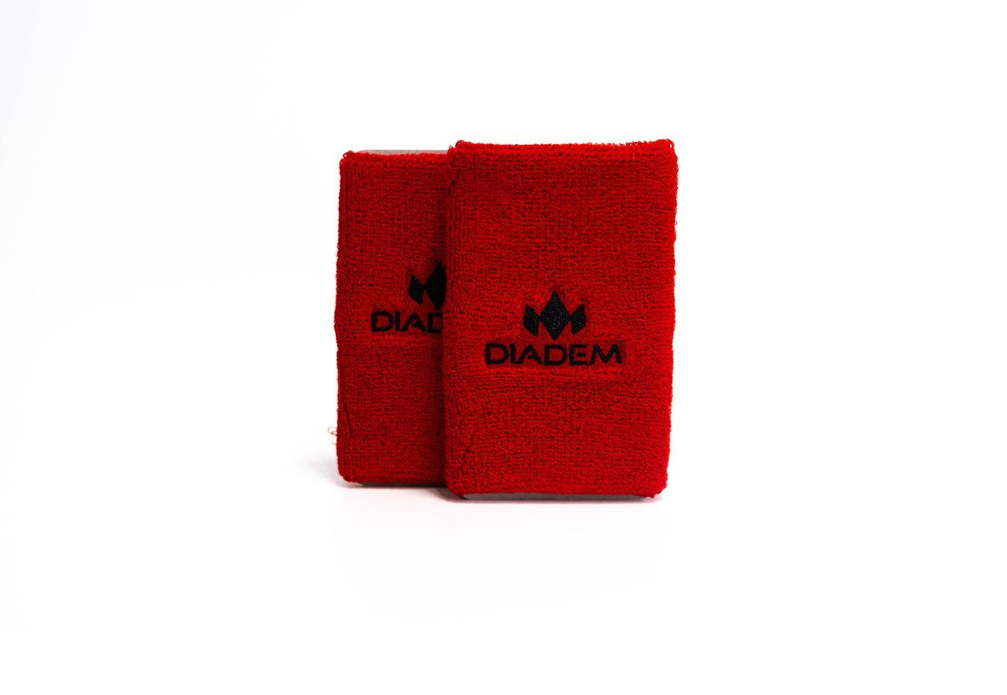 Two vibrant red Diadem Sports Logo 5" Wristbands stand upright on a white background, each with a black Diadem logo and text. These super absorbent, double wide wristbands are closely positioned, slightly overlapping.