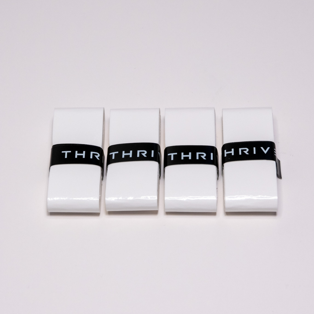Four white rectangular Overgrips (Super Tacky) by Thrive Pickleball are lined up side by side on a light background. Each grip is secured with a black band labeled "THRIV" in bold white letters, partially cropped at the edges.