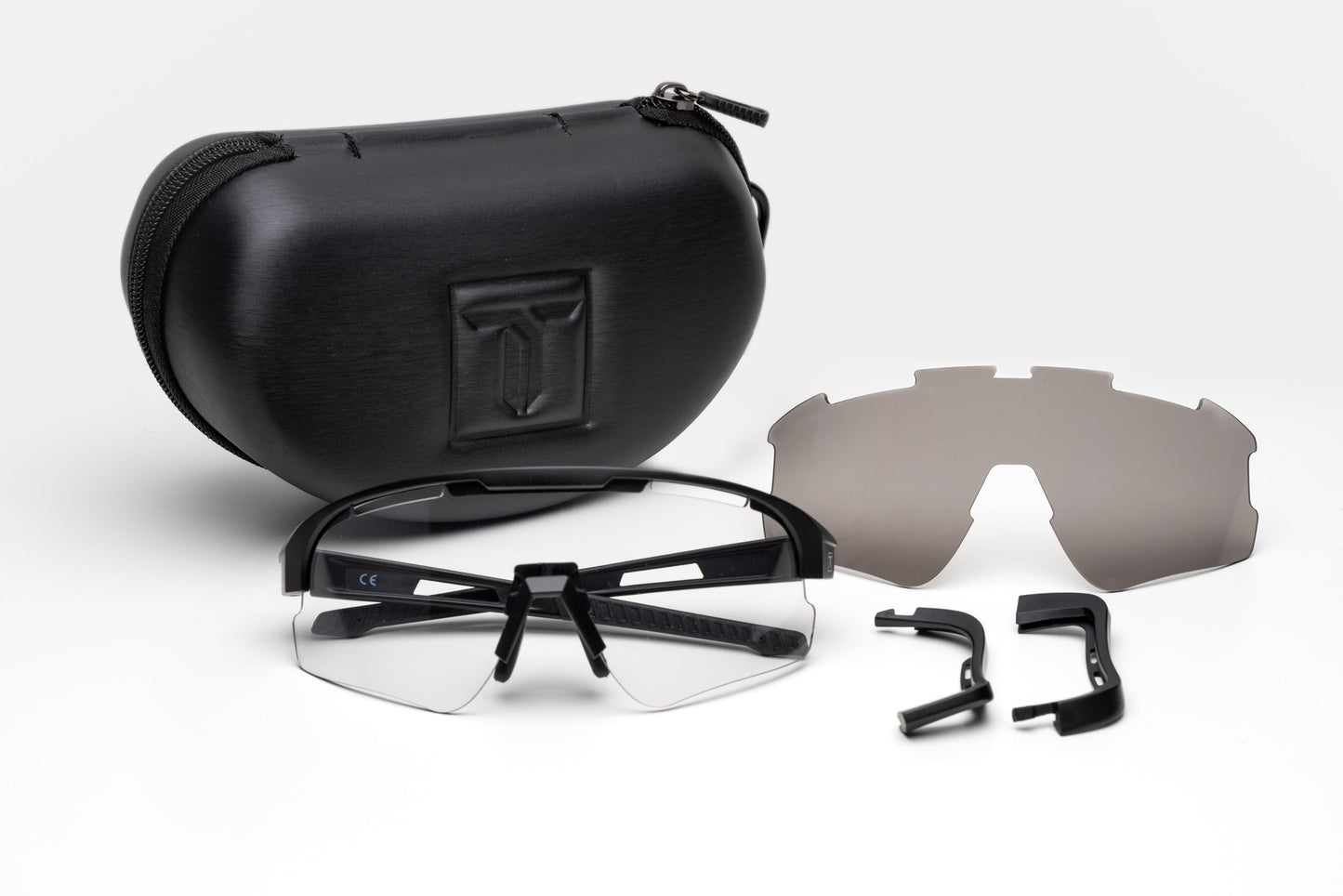 A black zippered case sits behind Thrive Pickleball’s Thrive Elite Pickleball Glasses with clear lenses, a dark lens, and two extra black temple arms—all laid out on a white surface. This set offers interchangeable eyewear options for pickleball.