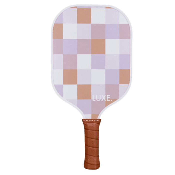 The LUXE Pickleball "Checker" paddle features a pastel checkered design in lavender, pink, white, and tan with a brown grip band. "LUXE." is printed in white near the bottom of the paddle’s face against a plain white background.