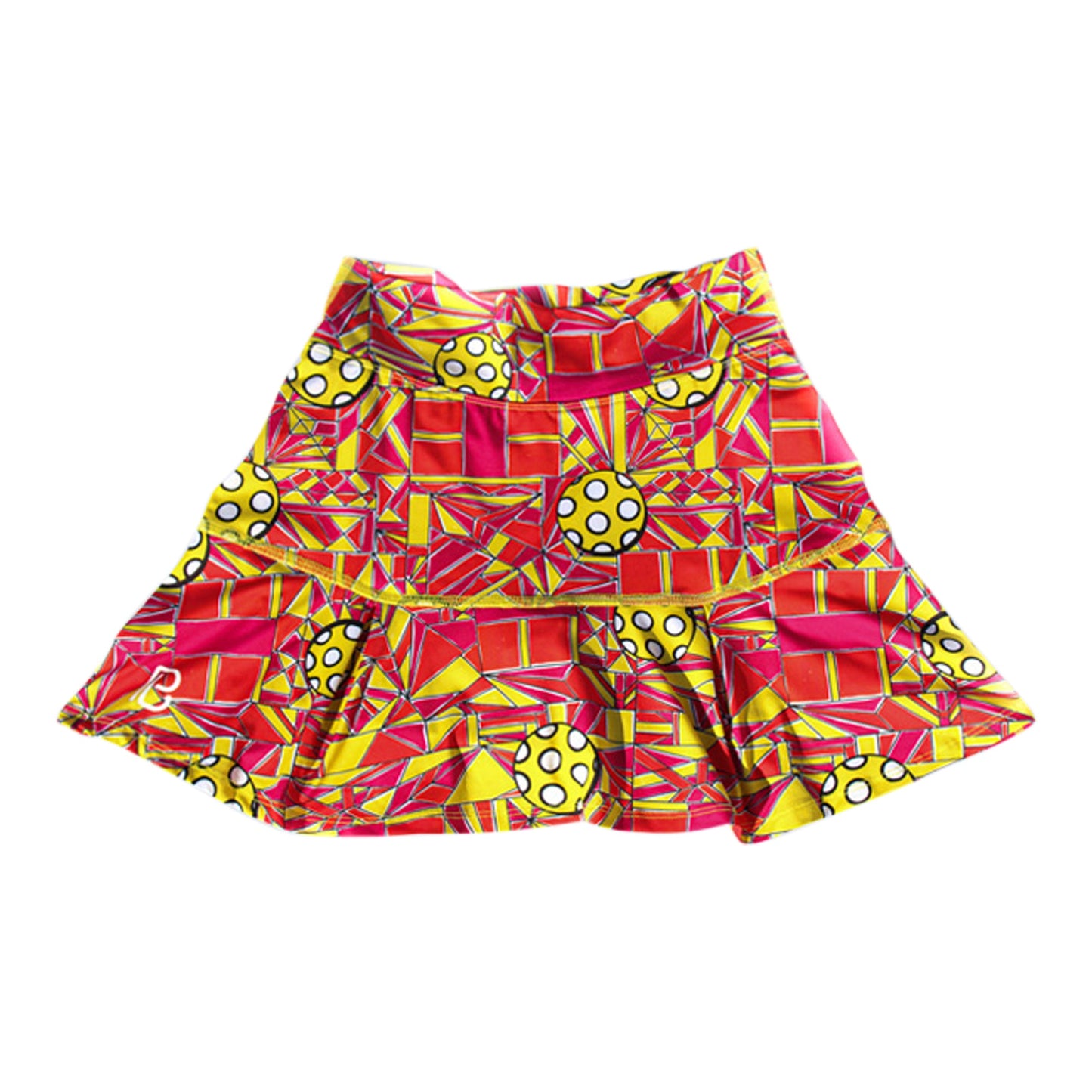 The PB Drop Pleat Skort Angle Shot 1 by Pickleball Bella features a flared design, vibrant red, yellow, and orange geometric shapes with bold spotted circles, a ruffled hem, structured waistband, and a crisp white background.