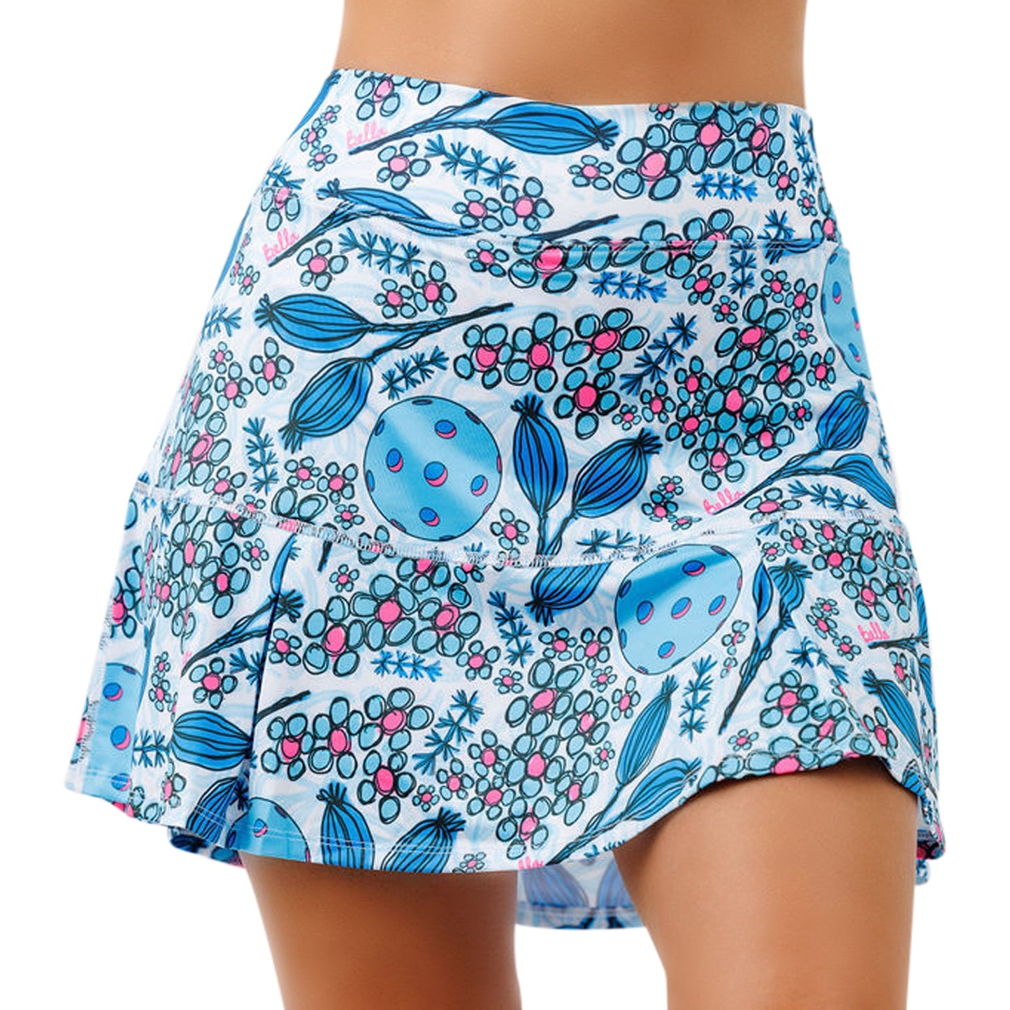 A person wears Pickleball Bella's PB Drop Pleat Skort Bloomers, featuring a figure-flattering fit with a wide waistband and blue, pink, and berry abstract botanical prints on a soft white background.