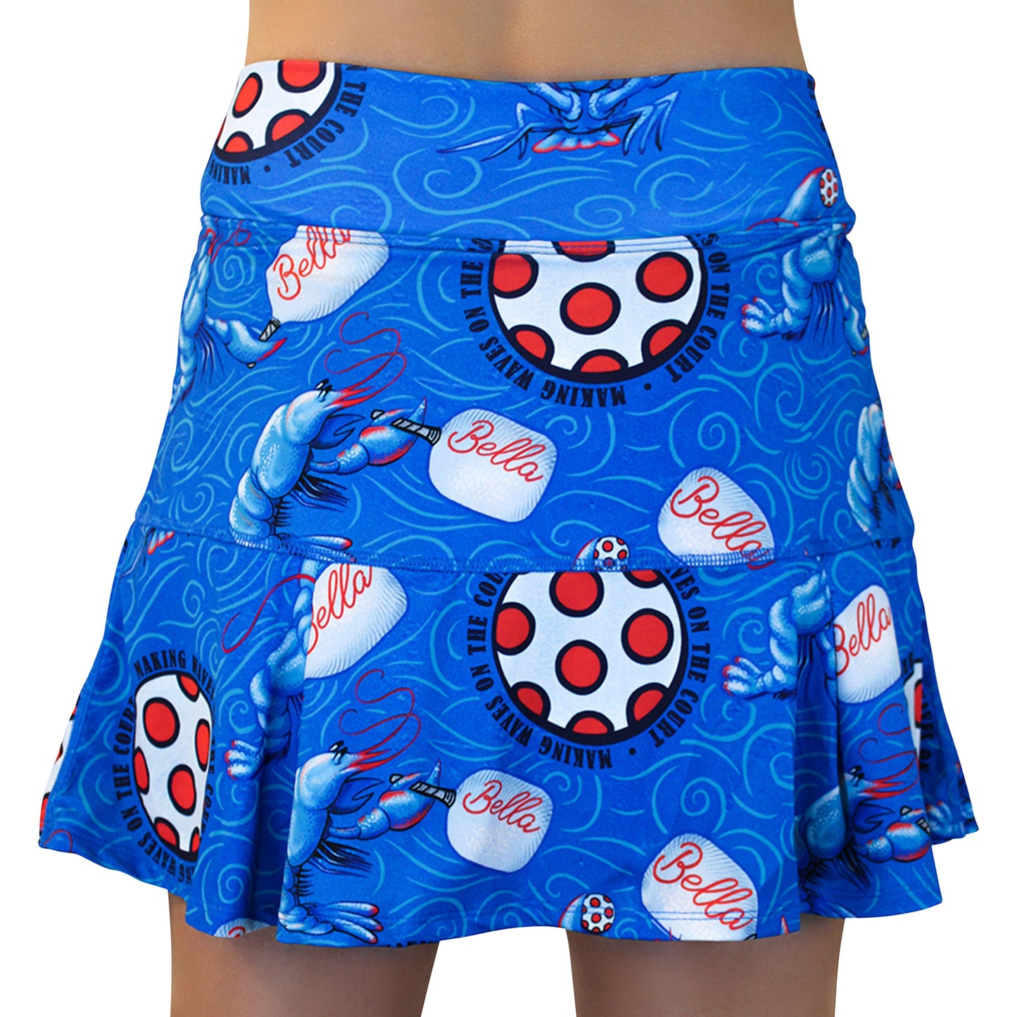 Pickleball Bella's PB Drop Pleat Skort Lobster Monster features a blue ruffled hem, red-and-white polka dots, cartoon blue crawfish, swirls, and playful “Bella” and “Making Waves” fonts—ideal as a fun pickleball skirt. Waist-down model shown.