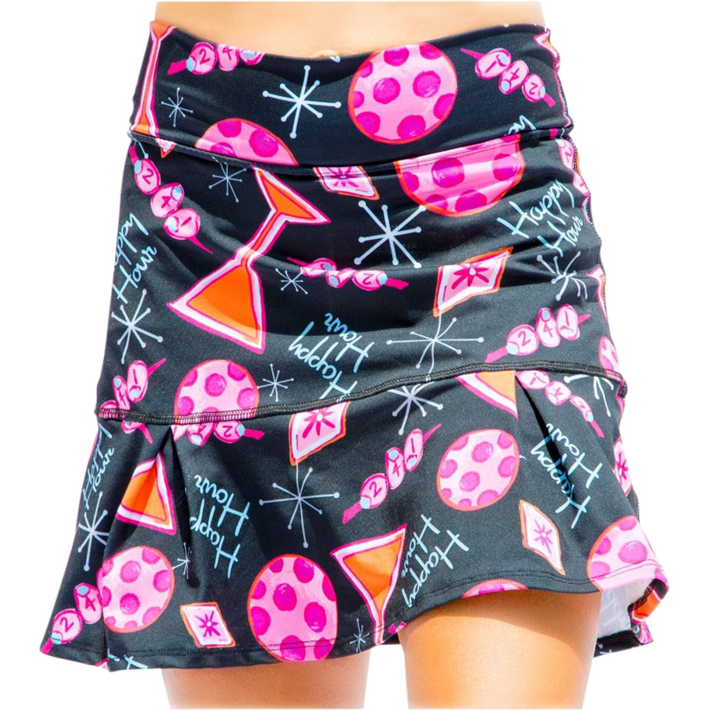A woman models the Pickleball Bella PB Drop Pleat Skort Martini 2-4-1 Happy Hour, a black, mid-century inspired flared skort featuring pink and red polka dots, hourglass shapes, starbursts, “Happy Hour” script, and a ruffled hem.