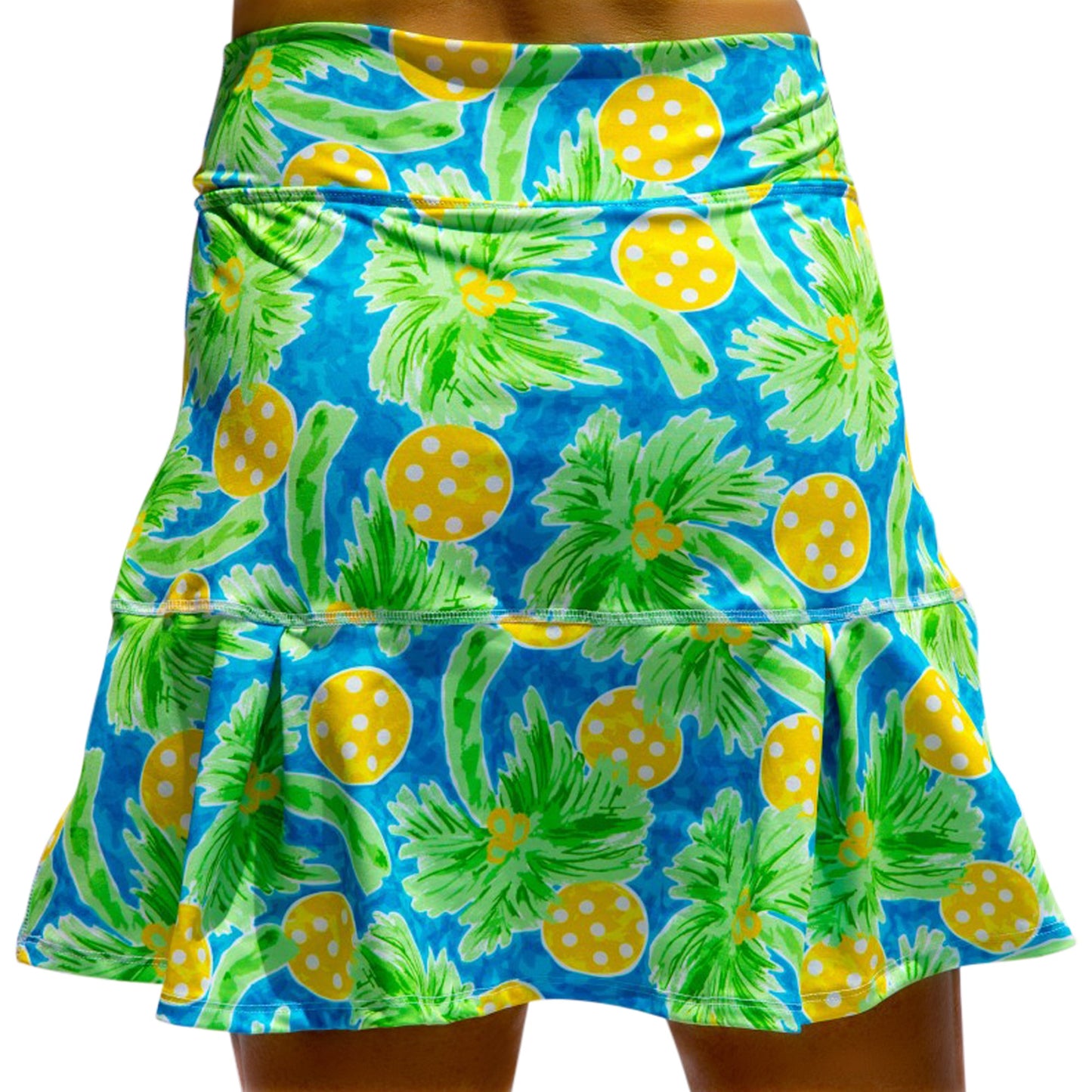 The Pickleball Bella PB Drop Pleat Skort Palms 1 features a blue base with green palm leaves and yellow polka-dotted circles plus a ruffled hem and fitted waistband for a playful, tropical vibe on the court or at the beach.