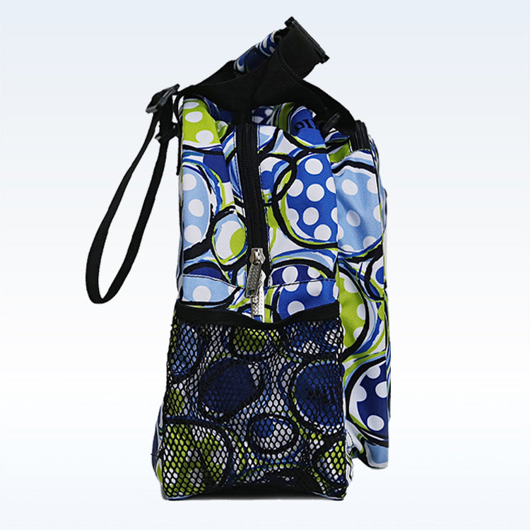 The Pickleball Bella PB Duffle Bag Dink 1 displays blue, green, and white abstract circles, shown from the side. Features include a zippered paddle pocket, black adjustable shoulder strap, and front mesh section, all set against a light blue background.