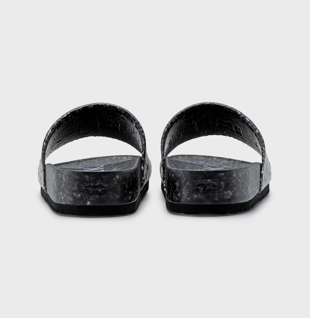 The Blumaka Fleks® East Beach Slide, shown from the back on a light gray background, features thick textured straps and flat soles designed to support alignment and promote athlete recovery.