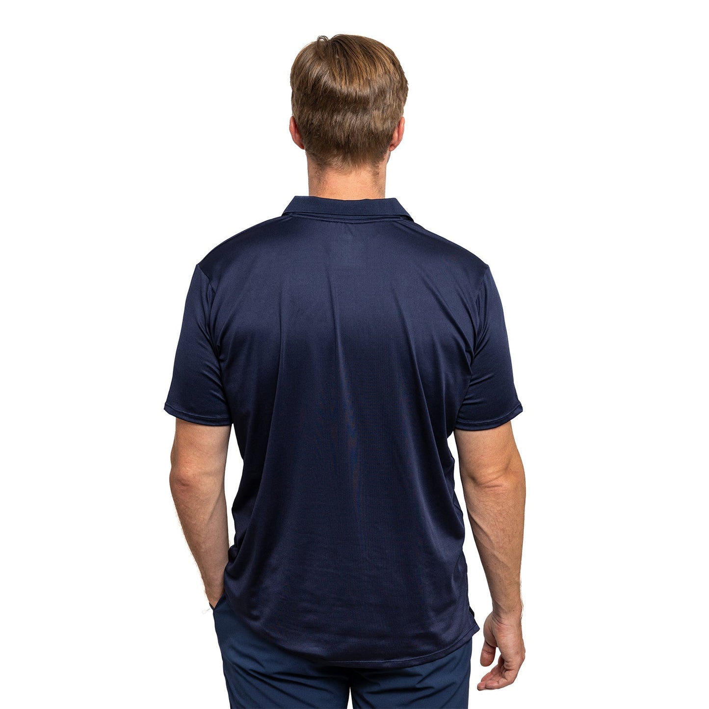 A man with short light brown hair stands with his back to the camera, wearing a navy Diadem Sports - Men's Essential Everyday Top and matching pants. The background is plain white, and his arms rest relaxed by his sides.