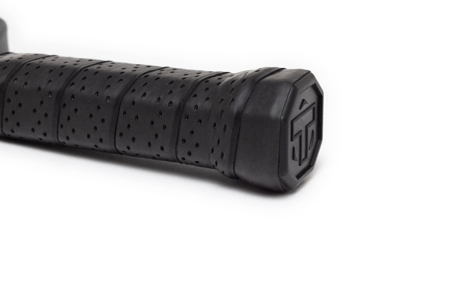 Close-up of the textured black rubber handle grip with small perforations and an octagonal end cap bearing a raised geometric logo on the TMPR Sports Expanse Beta LX hybrid pickleball paddle, shown against a plain white background.