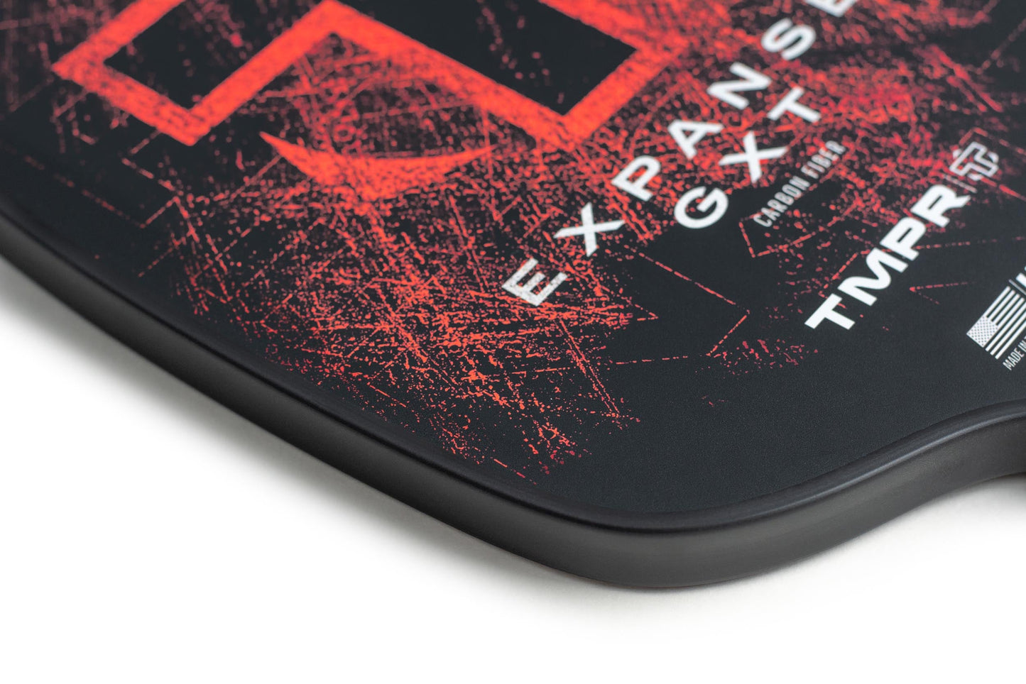 Close-up of the Expanse GXT pickleball paddle by TMPR Sports, featuring bold distressed red graphics, “EXPANSE GXT” text, carbon fiber face, TMPR logo, and a small American flag—showcasing quality craftsmanship made in the USA.
