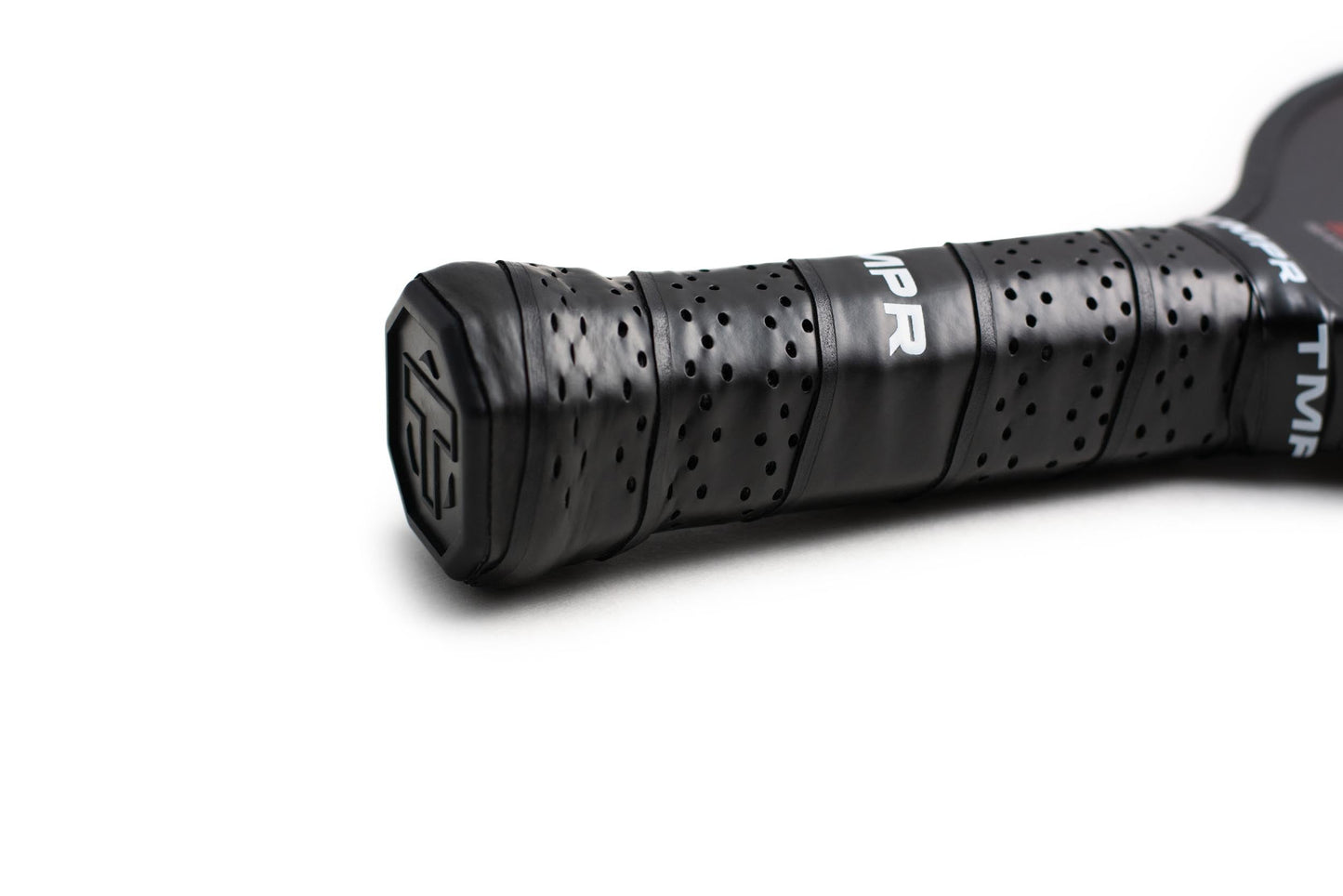 Close-up of the Expanse LX paddle’s black, perforated grip handle by TMPR Sports, photographed on a white background. “TMPR” appears on the grip with a logo on the end cap, emphasizing its textured design.