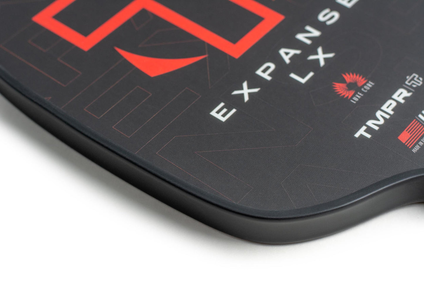 Close-up of the TMPR Sports Expanse LX pickleball paddle: black widebody design with bold red geometric graphics, “Expanse LX” text, and TMPR Sports logo on the smooth fiberglass face, highlighting subtle patterns and branding.