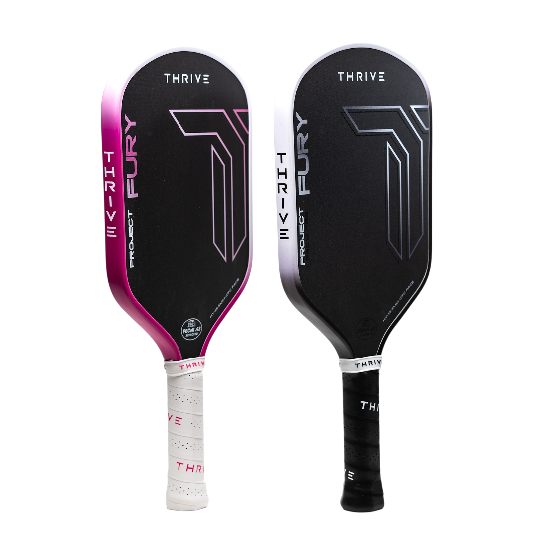 Two Thrive Pickleball FURY Hybrid 15.5 MM (GEN 3.5 POWER SERIES) paddles stand upright—one fading black to pink, one black to white—featuring bold geometric graphics, modern designs, and an advanced floating core for peak performance.