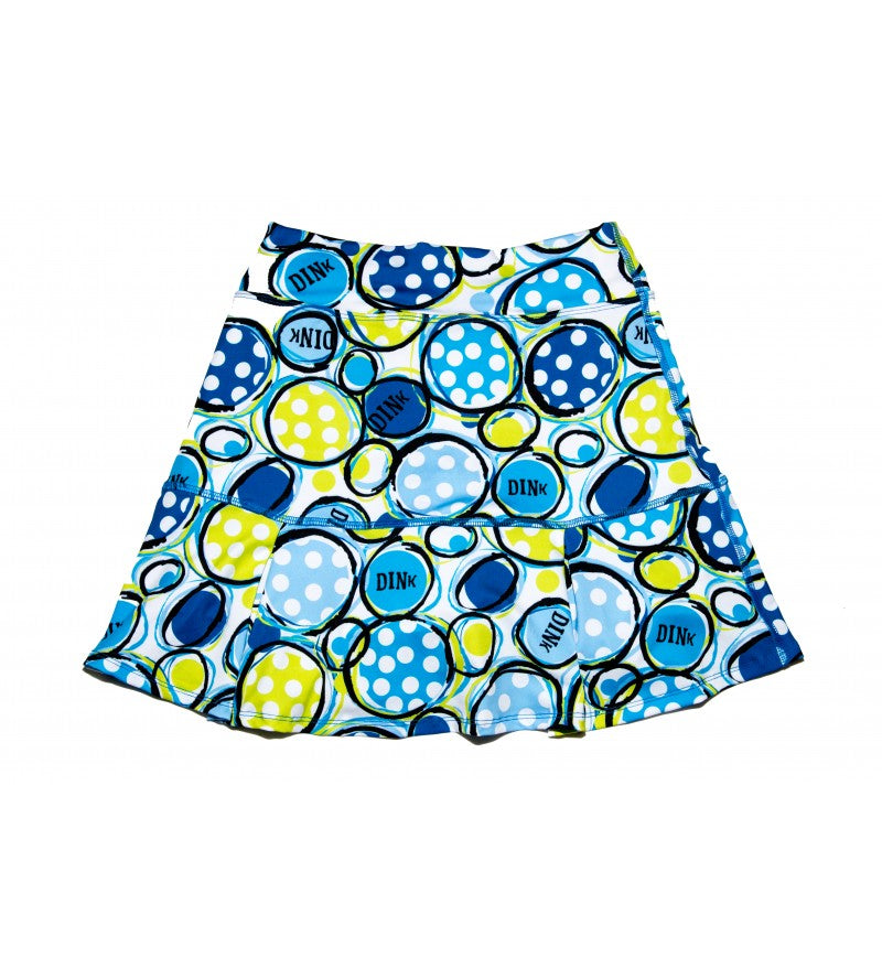 The PB Drop Pleat Skort Dink 1 by Pickleball Bella features a flared, figure-flattering silhouette with overlapping blue, yellow, and green circles, white polka dots, bold "DINK" lettering, and is lightweight for sporty style.