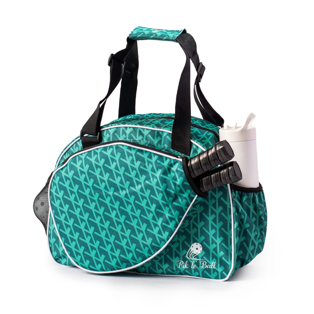 The Court Couture Green Premium Women's Pickleball Bag by Pik'le'Ball Sports features a teal arrow pattern, black handles, white trim, and a front “Pickleball” logo. Side pockets hold a water bottle and grips. The bag stands upright on a white background.