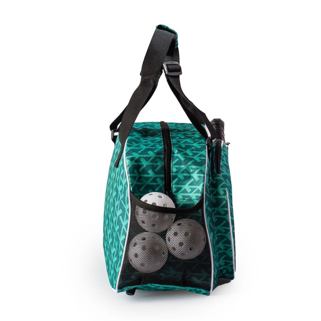 The Pik'le'Ball Sports Court Couture Premium Women's Pickleball Bag features a green geometric design, black strap and handle, upright shape, mesh pocket with three white balls, paddle sleeve, and multiple compartments against a plain white background.