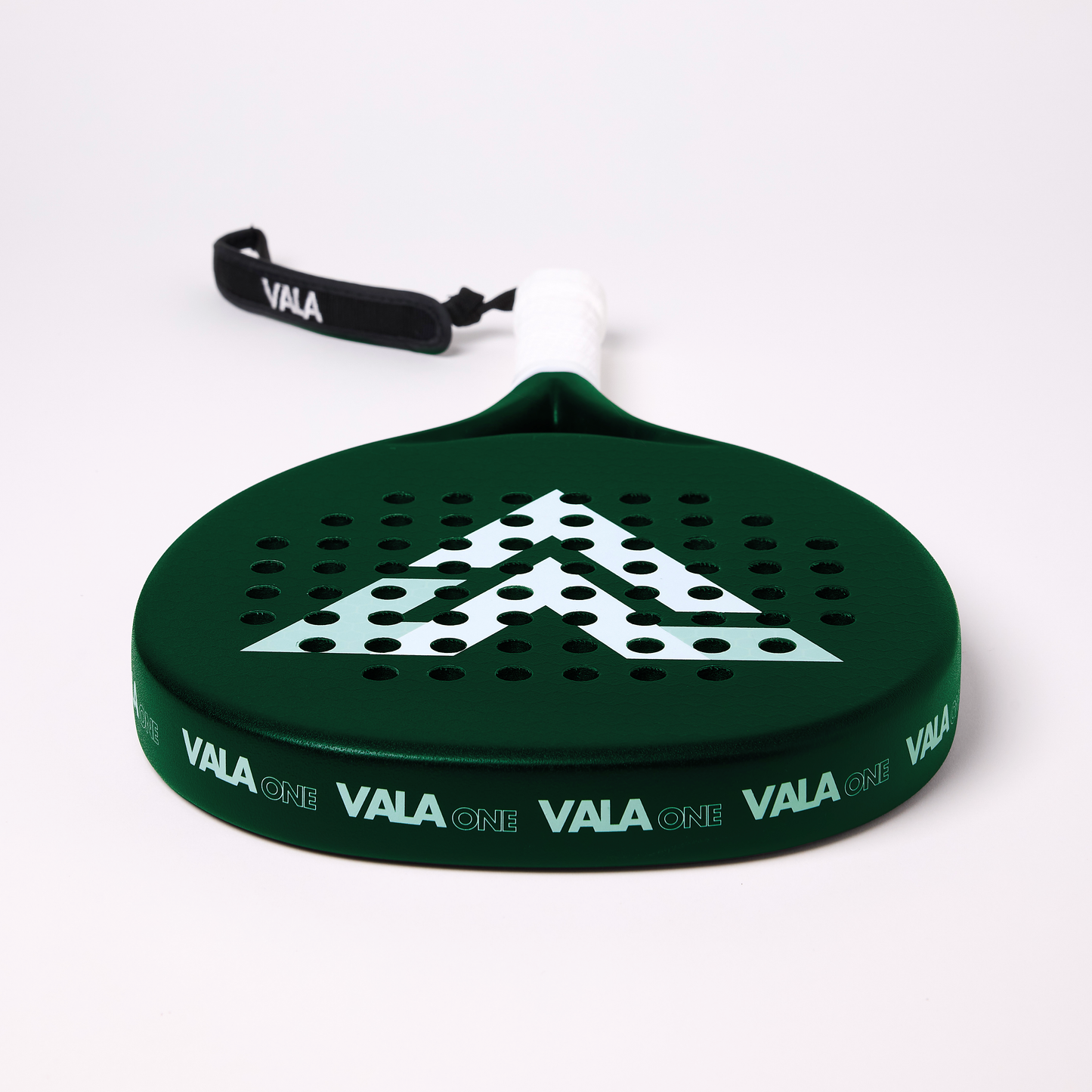 The VALA One (Green Edition) by VALA features a dark green racquet with a white grip, black VALA wrist strap, EVA foam core for control, bold white geometric face design, circular holes, and "VALA ONE" printed on the edge.