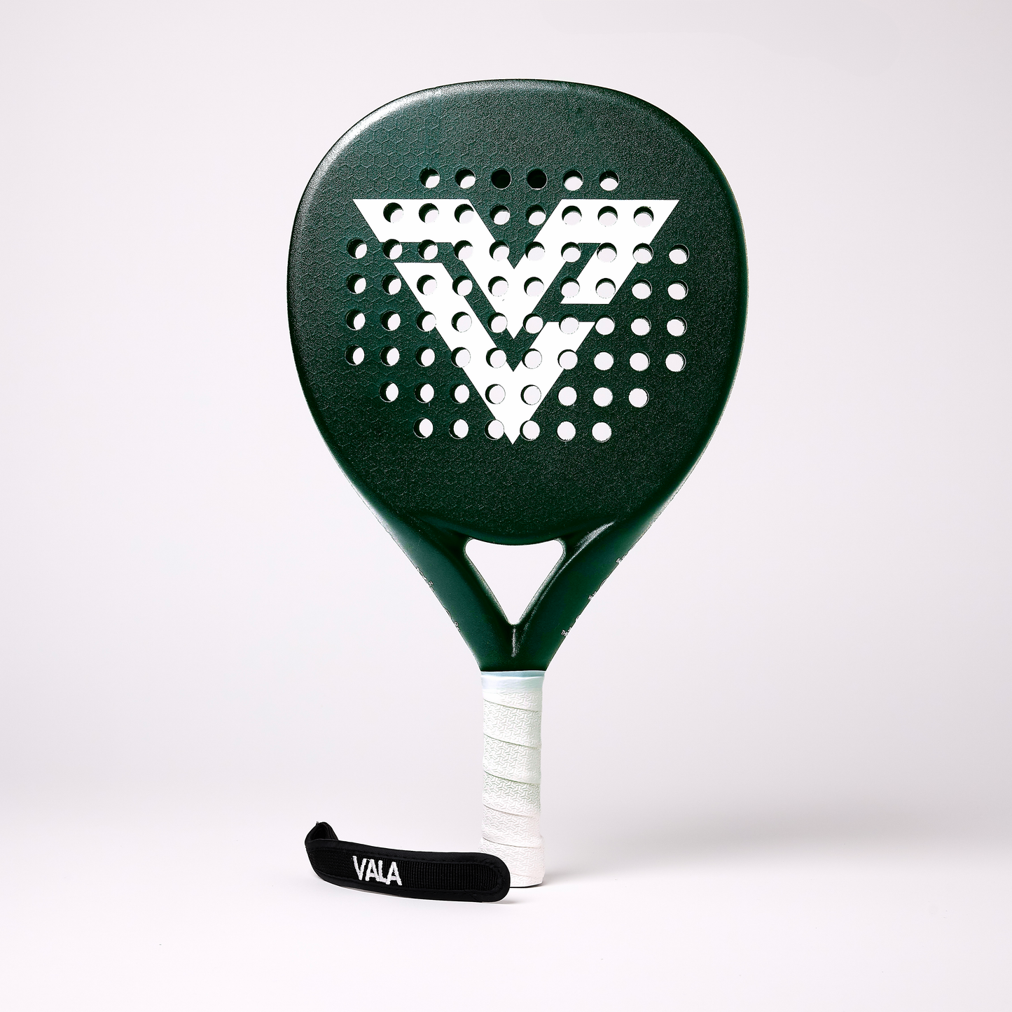 The VALA One (Green Edition) padel racquet from VALA features a large white “V” logo, round perforations for control, a white grip, and black wrist strap with “VALA” in white. It stands upright on a plain white background.