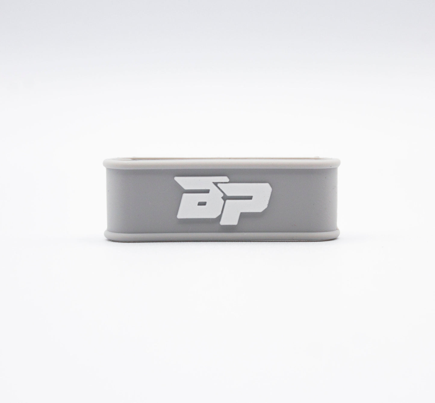 A light gray rectangular silicone Paddle Band by Bodhi Performance with rounded edges and a white BP logo is centered on a white background. Its simple, modern design makes it an ideal pickleball paddle accessory.