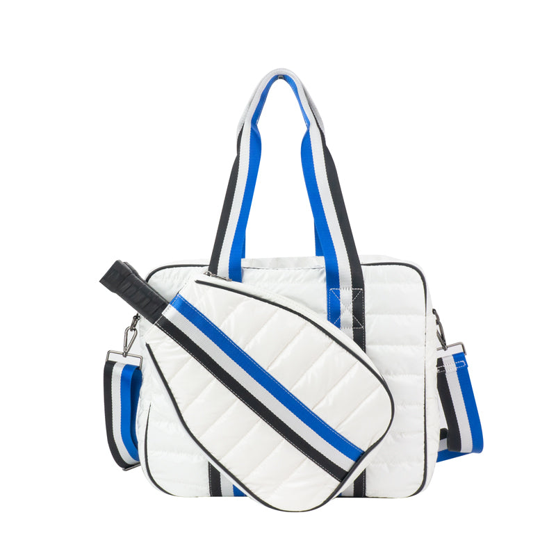 The Quilted Puffer Pickleball Tote in White by Runway Athletics features blue and black striped handles, a matching front zippered racquet cover, plus both shoulder and crossbody straps for versatile carrying.