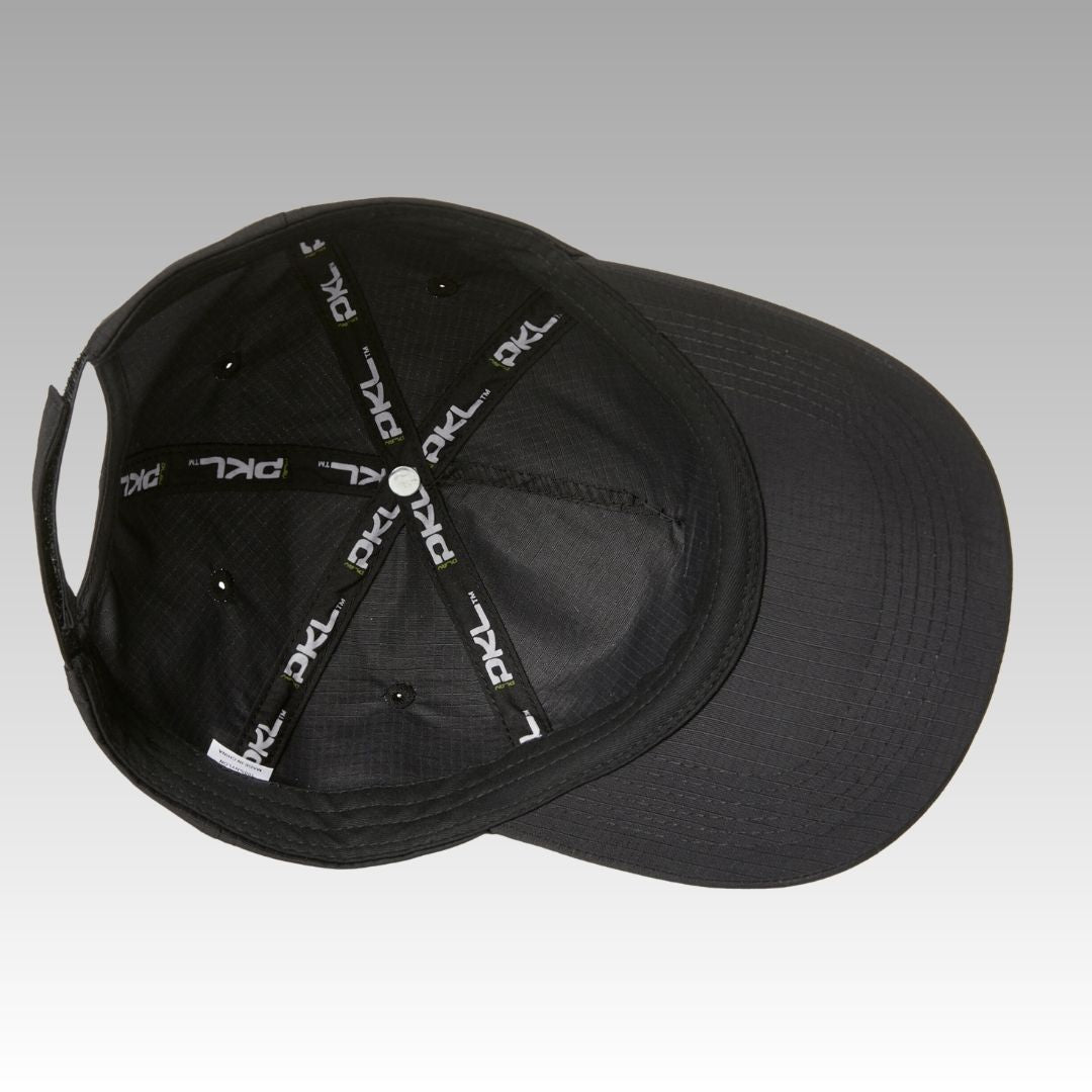 The Hi Hat Pickleball Hat by Playly Store, shown from above, reveals black fabric strips with white "PKL" text in an X pattern and small ventilation holes inside. Made from moisture-wicking fabric, it sits on a smooth gray gradient background.