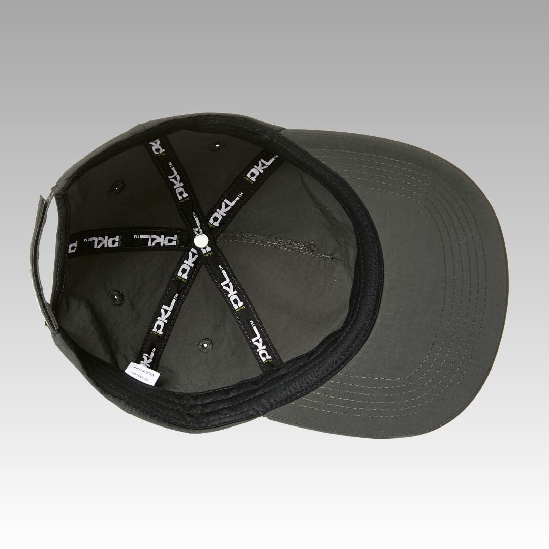 The Hi Hat Pickleball Hat by Playly Store is a dark gray ripstop nylon cap with a curved brim, metal eyelets, and reinforced inner seams featuring black straps with repeated white PKL logos, shown from above on a gray gradient background.